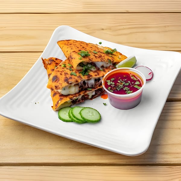 Three cheesy birria quesadillas with cilantro, lime, cucumber, and a side of red dipping sauce.