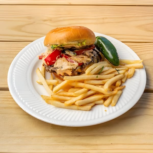 Aztk burger with red peppers, sauce, and a side of fries and a jalapeño on a white plate.